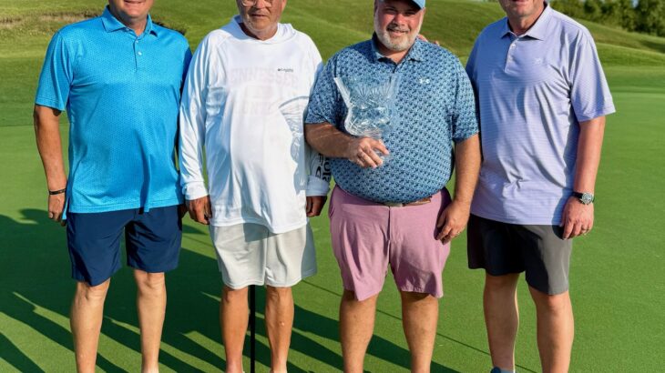 Four men standing on a golf course.