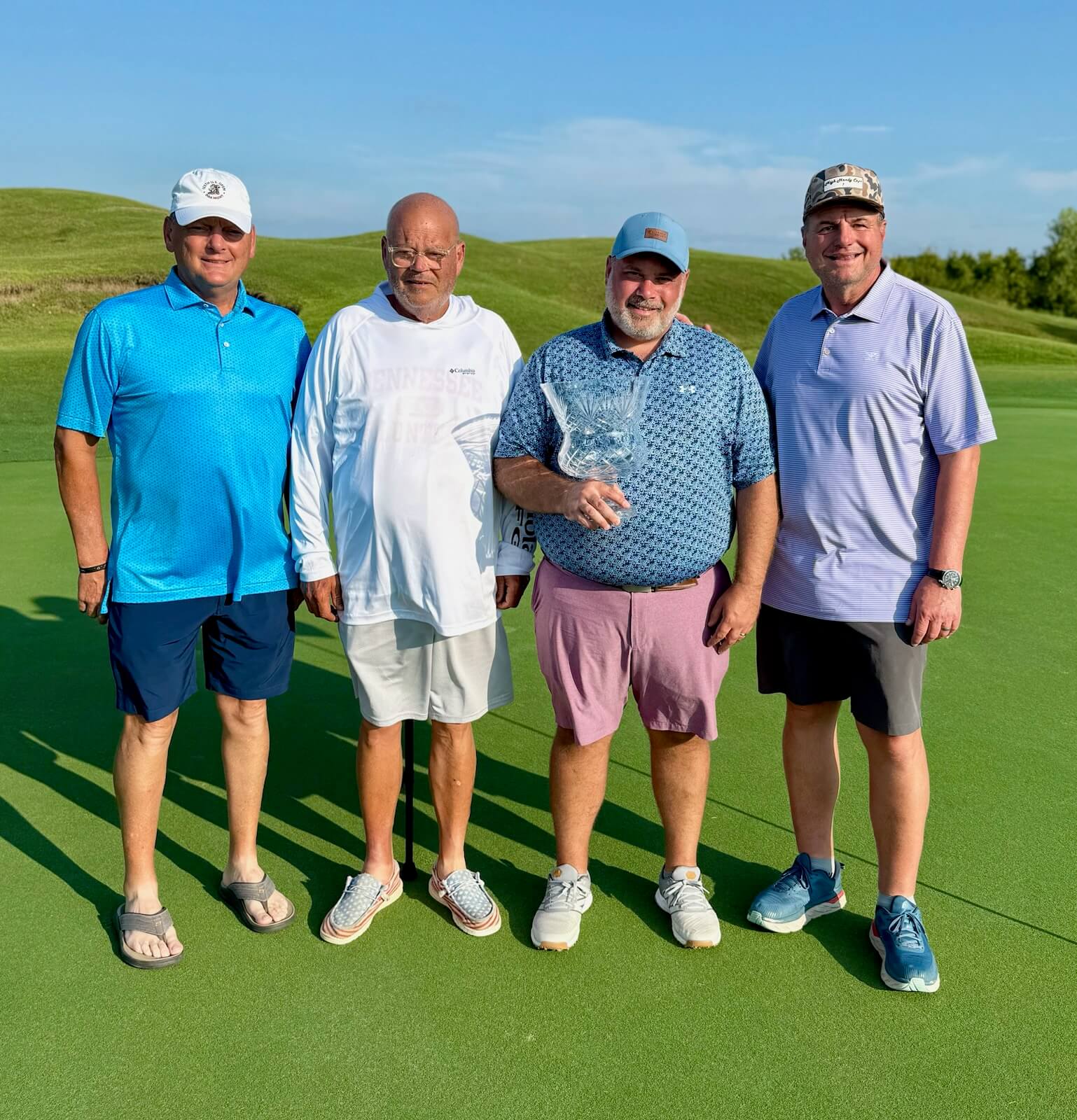 Four men standing on a golf course.